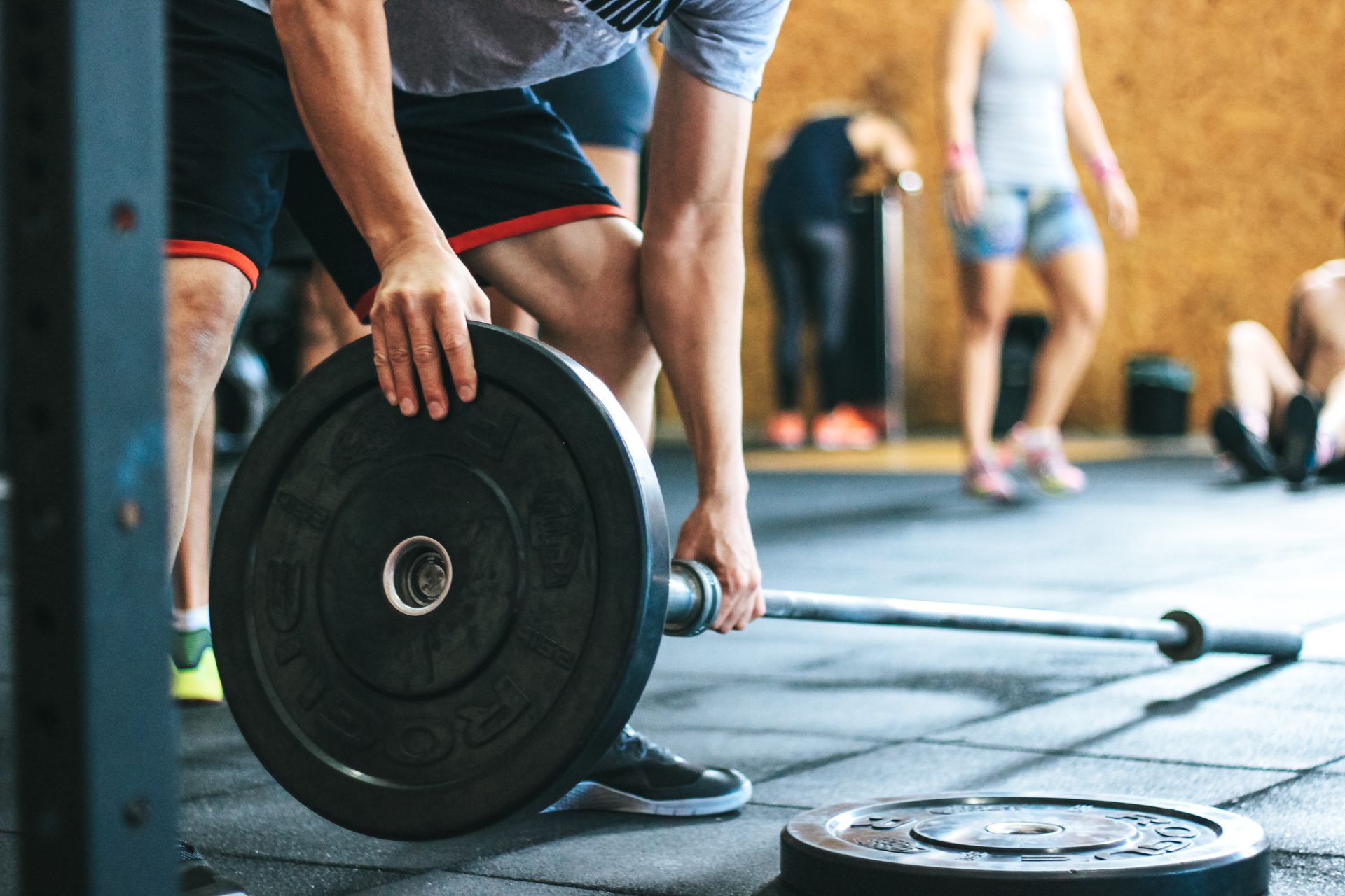 A lifter loading a plate onto a barbell on a gym floor