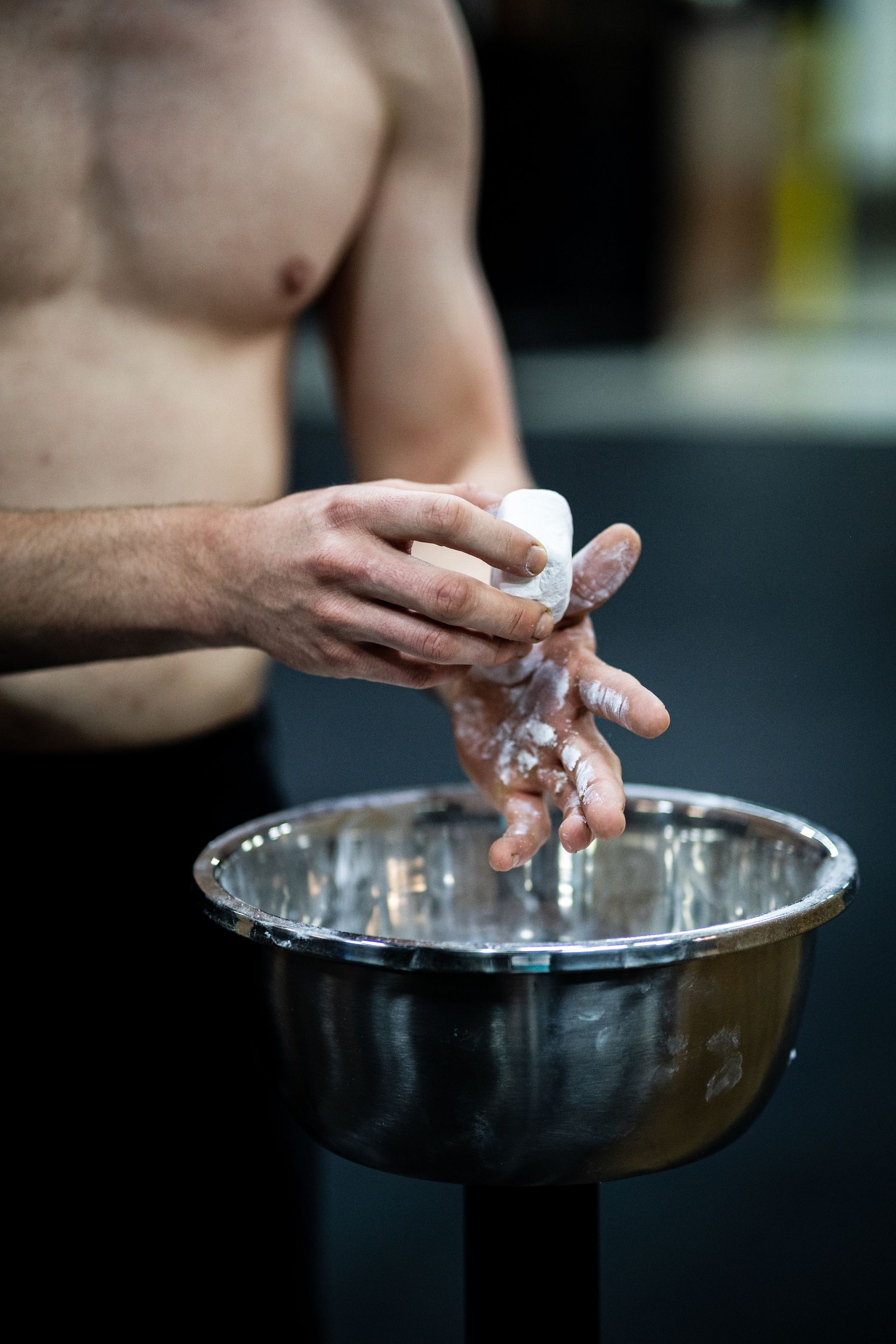 A lifter chalking his hands from a bowl before training in an indoor gym
