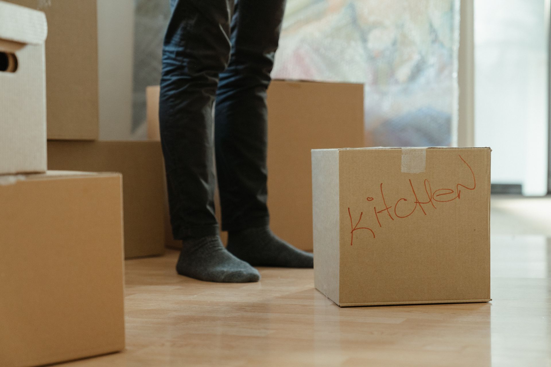 A person standing in a room among labeled cardboard moving boxes