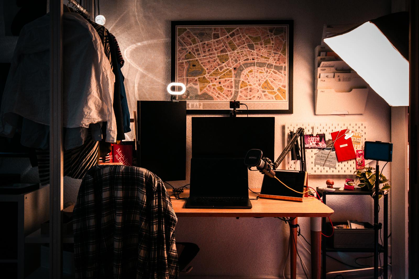 A dark creator studio: desk, microphone, ring light, and laptop in warm low light