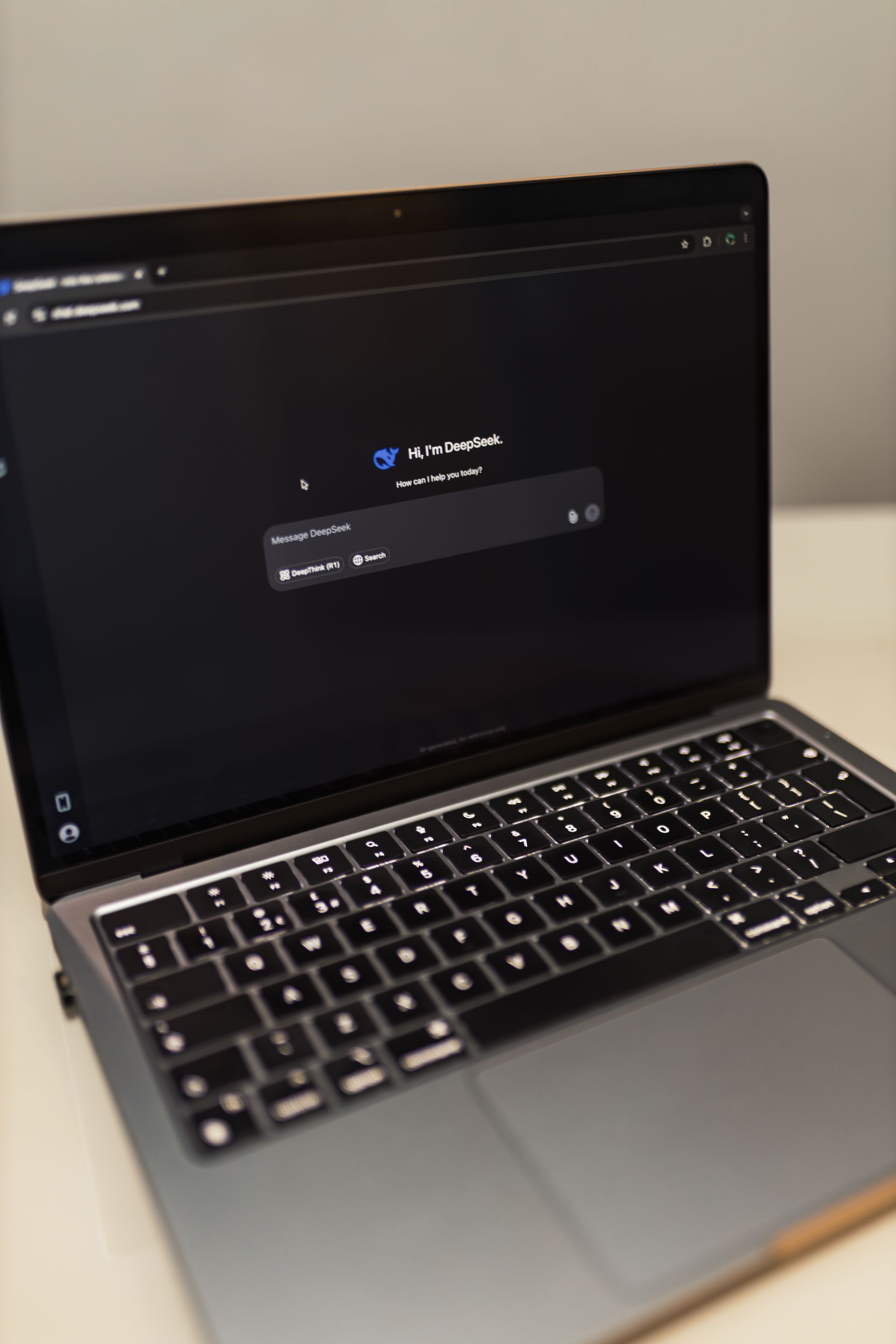 A laptop showing a dark-mode AI chat interface in a dimly lit room