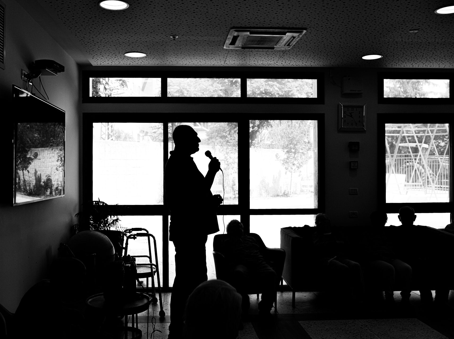 A facilitator speaking to a seated audience in a darkened room