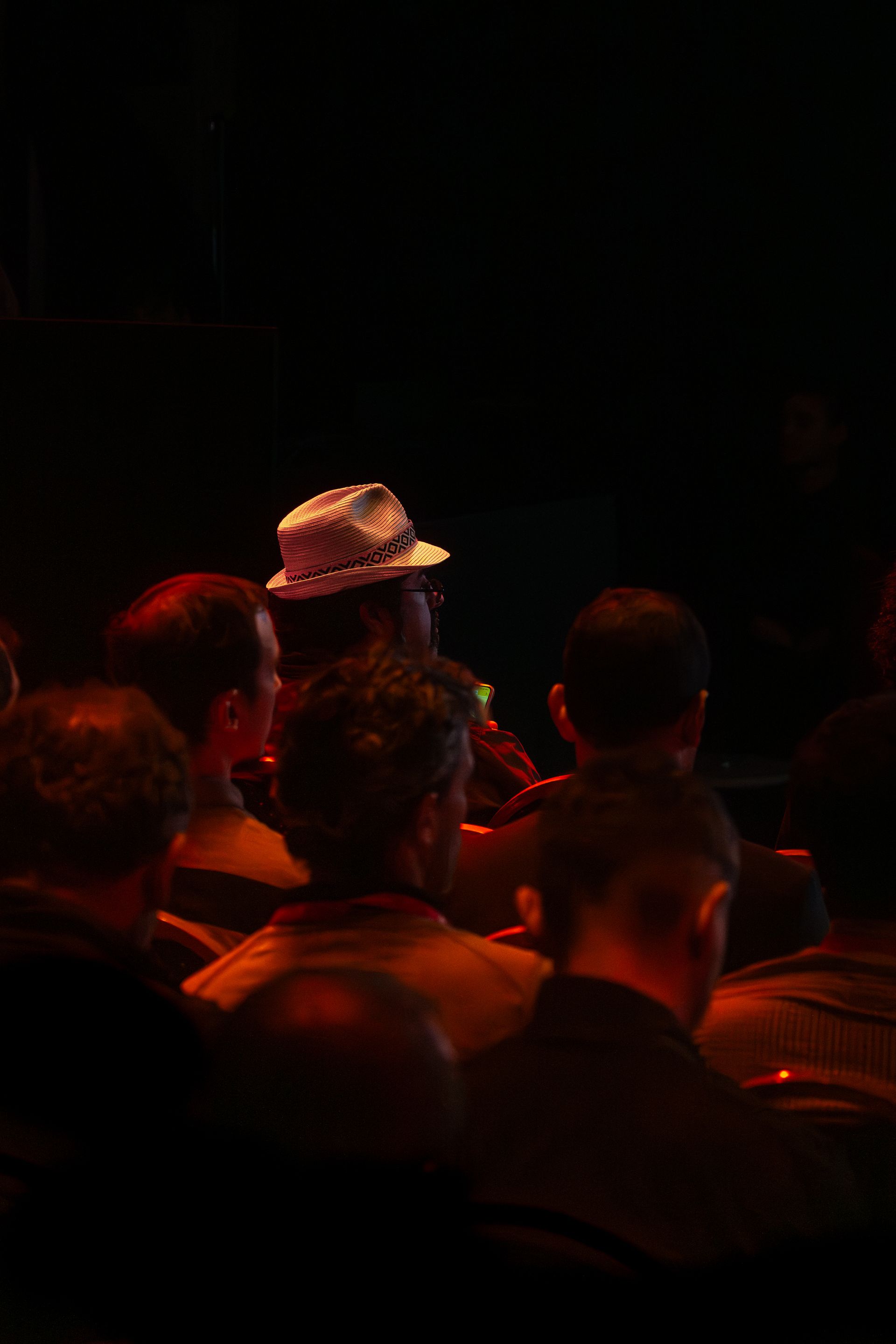 An audience at a live session in dim lighting, one participant catching the light